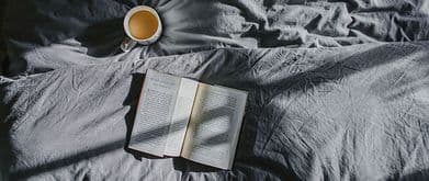 book on bed with coffee