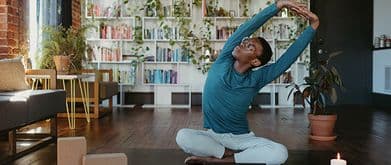 person doing yoga in front of books and plants