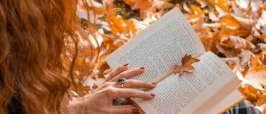 woman reads a book against a background of foliage