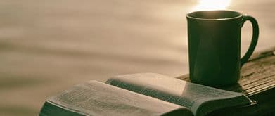 book and coffee at sunset over water