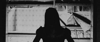 Black and white silhouette of woman standing in a doorway 