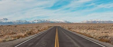 A highway through the midwest with snowy mountains in the background